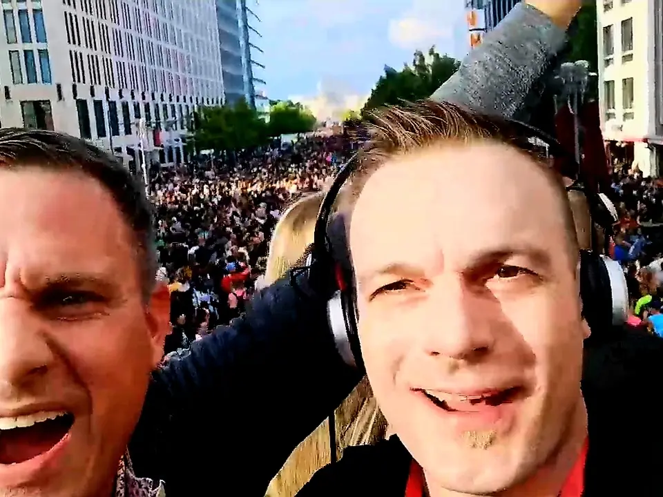 Simon und Thomas auf einem Umzugswagen über einer grossen tanzenden Menge